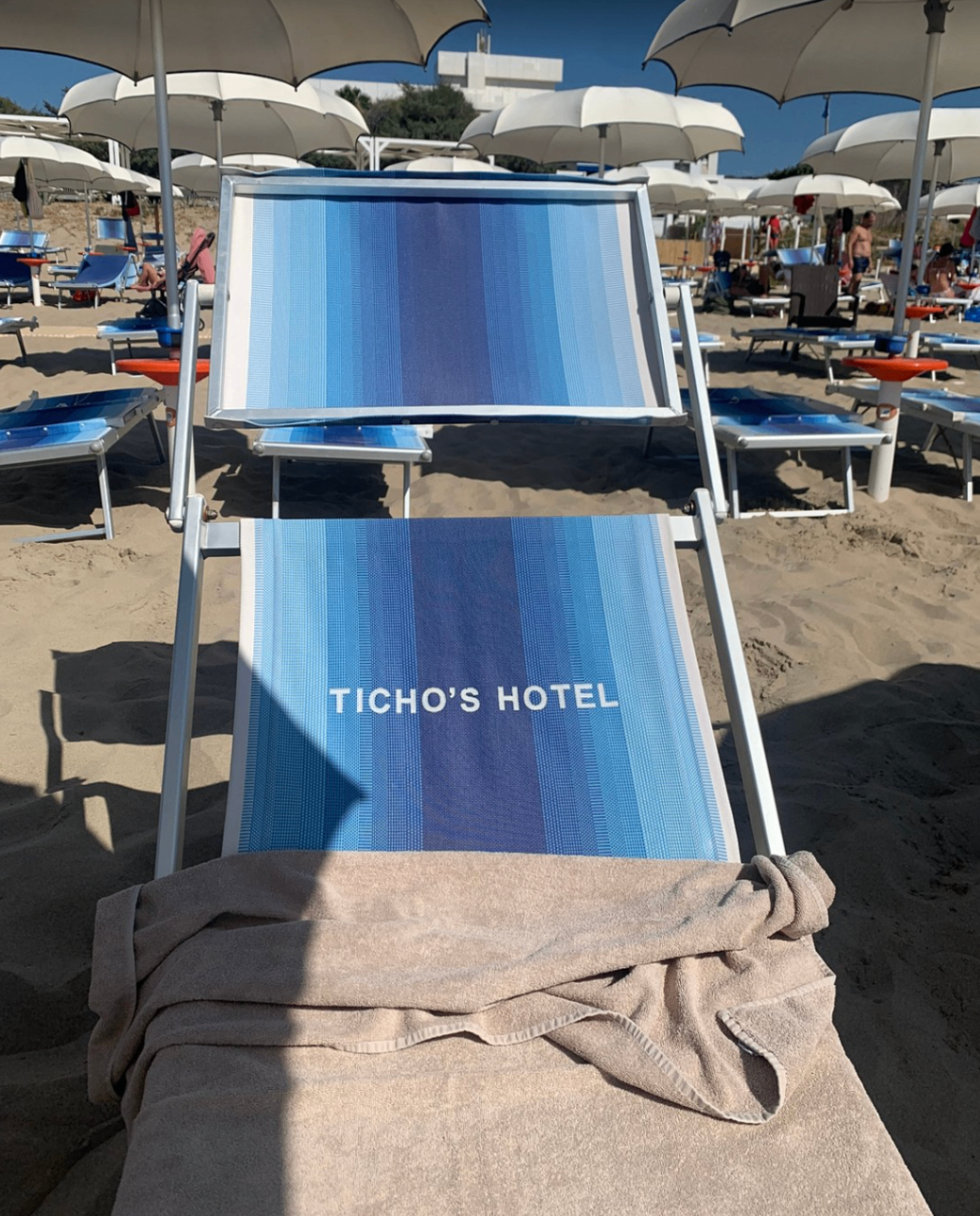 Lettino brandizzato Ticho's Hotel tra gli ombrelloni