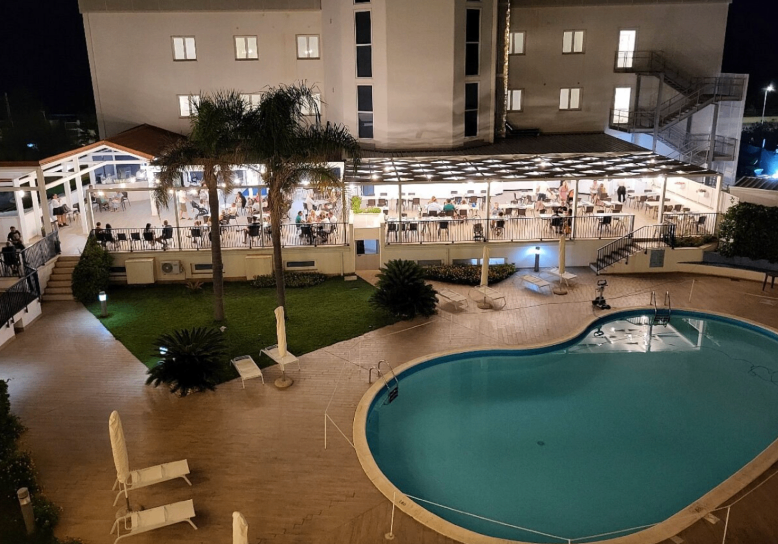 Piscina e area ristorante illuminate di sera